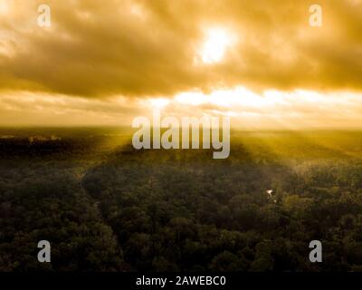 Luftbild von Sonnenstrahlen, die durch Wolken auf Wald im Norden Floridas scheinen. Stockfoto