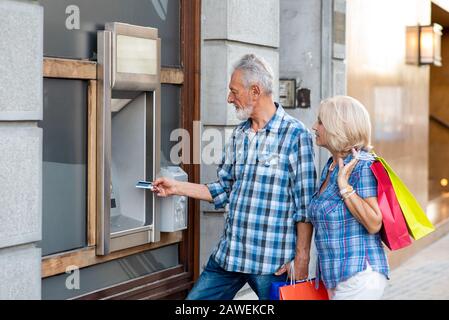 Senior Paar mit Tüten mit Geldautomat Stockfoto