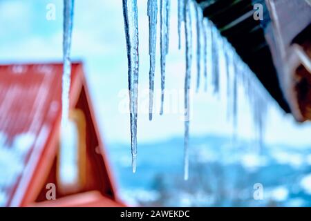Starker echter Winter im Süden Polens - riesige Eiszapfen hängen vom Dach gegen den blauen Sonnenhimmel Stockfoto