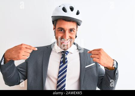 Junger, gutaussehender Business man Fahrradhelm und drahtlose Kopfhörer über isoliertem Hintergrund, der selbstsicher mit einem Lächeln im Gesicht aussieht und sich mit FI zeigt Stockfoto