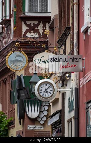 Miltenberg, DEUTSCH - 07.07.2019: Moderne Uhr und Hinweisschilder und an den mittelalterlichen Fachwerkbauten in der Hauptstraße in der Altstadt Stockfoto