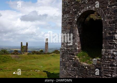 Ruinen der Wheal Jenkin Mine, Teil des Bellingham Shaft Engine House im Vordergrund, Caradon Hill, in der Nähe Von Minions, Bodmin Moor, Cornwall, England Stockfoto