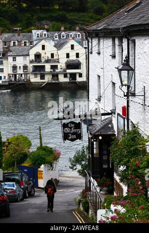 Frau mit Rucksack, die die Hall Terrace entlang geht, vorbei am Old Ferry Inn, River Fowey im Hintergrund, Bodinnick, nahe Fowey, Cornwall, England Stockfoto