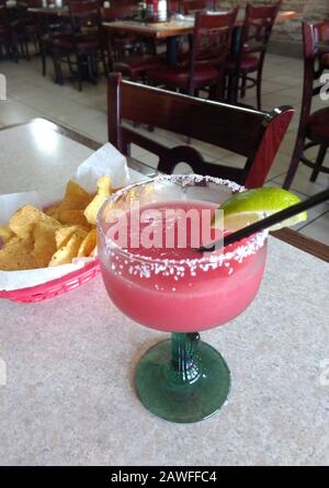 Tortilla-Chips in einem Korb und eine große süße Erdbeere margarita mit einem gezuckerten Rand und Kalkgarnierung Stockfoto