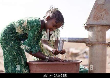 Armer Westafrika-Youngster mit reinem Wasser in einem ländlichen Dorf Stockfoto