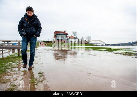 Ein Mann, der durch das Wasser läuft.Überschwemmungsgebiete am Rheinufer und andere größere Flüsse werden voraussichtlich später am Wochenende unter Wasser sein. Nijmegen ist eine der niederländischen Städte, die jetzt von diesem hohen Wasserstand betroffen sind. Die Waalkade, die Zone näher am Fluss, wurde für den Verkehr gesperrt und es wird erwartet, dass das Wasser eine Höhe von mehr als 11 Metern über dem Meeresspiegel erreichen kann. Das Rheinwasser bei Lobith, wo der Fluss in die Niederlande übergeht, soll in den kommenden Tagen rund 14 Meter über NAP erreichen. NAP ist die Basis, mit der gemessen wird, wie hoch o Stockfoto