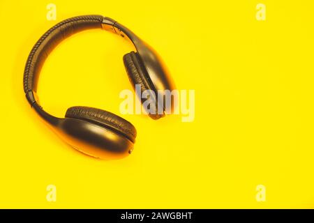 Schwarze Kopfhörer auf gelbem Hintergrund. Kabellose Kopfhörer Stockfoto