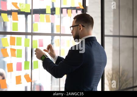 Der Geschäftsmann bereitet den Sitzungssaal für die Verhandlungen vor, bei denen Post-it an der Wand befestigt wird Stockfoto