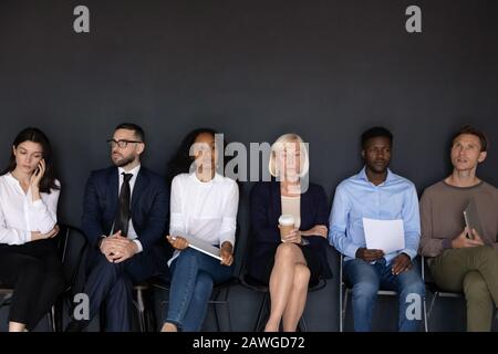 Multikulturelle Bewerber warten auf Bewerbungsgespräch auf Stühlen Stockfoto