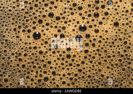 Kaffeeschaum mit Blasenmakro-Textur. Aufschäumen Sie den Hintergrund Stockfoto