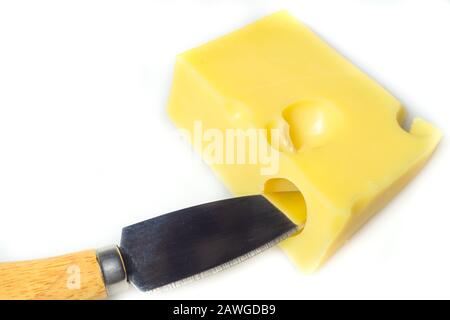 Käse mit einem auf Weiß isolierten Käsemesser. Stück Käse mit Löchern Stockfoto