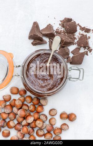 Hausgemachte vegane Haselnussschokolade in einem kilner Glas mit ungeschälten Haselnüssen und Brocken dunkler Schokolade Stockfoto