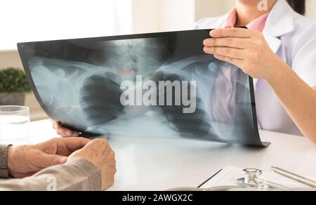 Arzt, der Röntgenbild oder Röntgenbild im Krankenhaus bei Patienten hält Stockfoto