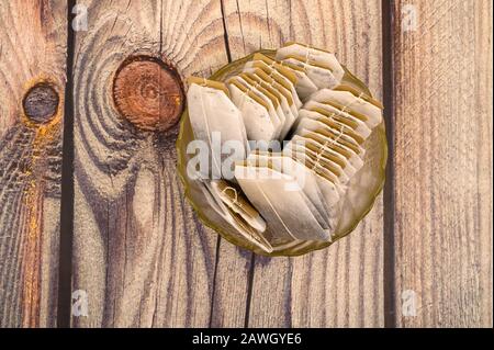 Teebeutel in einer Glasvase auf Holzhintergrund. Nahaufnahme Stockfoto