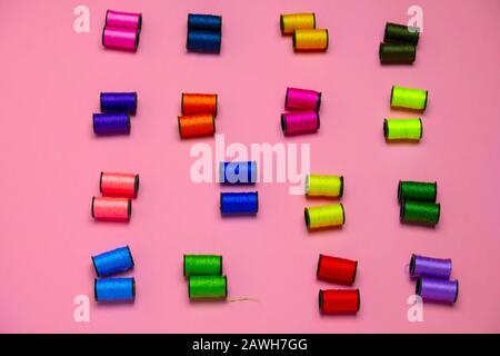 Draufsicht kreatives Stillleben flach lag mit Rollen aus bunten Fäden Muster auf einem pinkfarbenen Hintergrund Stockfoto