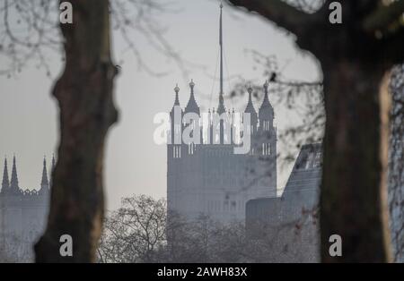 Fernblick auf Die Häuser des Parlaments Victoria Tower durch Bäume vom St James's Park im Zentrum Londons Stockfoto