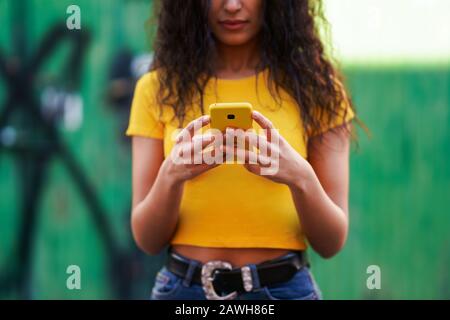 Junge Araberin, die mit ihrem Smartphone auf der Straße spazieren ging Stockfoto