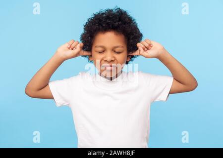 Möchten Sie nicht zuhören. Portrait des ungehorsamen kapriziösen kleinen Jungen mit lockigem Haar, das Ohren bedeckt, um keinen Rat zu hören, Erziehung zu ignorieren und zu parentieren. Stockfoto