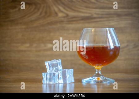 Komposition aus Glas mit köstlichem Whisky neben Eiswürfeln. Auf Eichenblatten Stockfoto