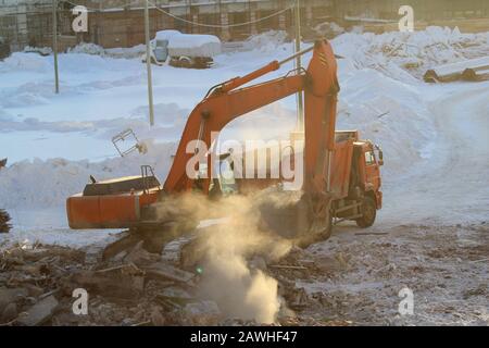 Bagger lädt im Winter in Russland Erde in einen LKW an einer Baustelle. Stockfoto