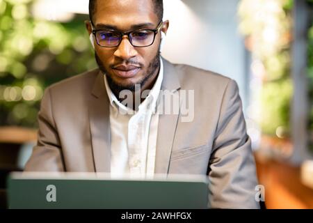 Fokussierter Afro Kerl in Brille, der im Büro Musik hört Stockfoto