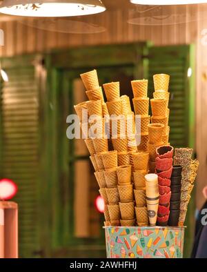 Farbenfrohe Eiskegel und Waffelstäbchen in einem Geschäft, süßes Dessert mit warmem Innenlicht. Stockfoto