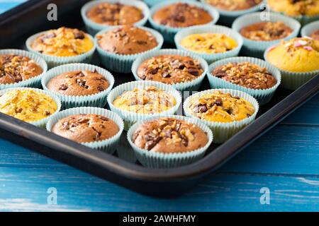 Frische Muffins mit Nüssen und Schokolade auf dem Papierkuchenhalter. Stockfoto