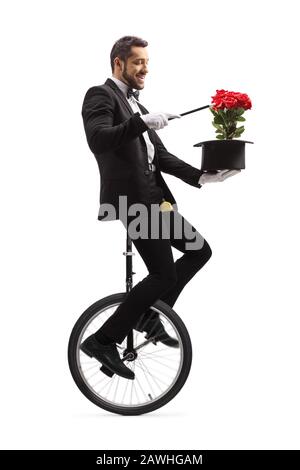 Magier, der auf einem Einrad mit Zauberstab, Hut und roten Rosen auf weißem Hintergrund auftrat Stockfoto