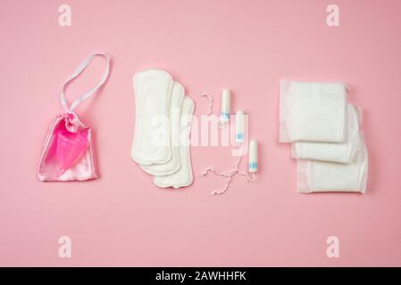 Frauenpolster, Tampons und Menstruationsbecher liegen isoliert auf pinkfarbenem Hintergrund. Konzept Frauenschutz Stockfoto