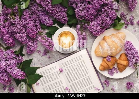 Frühlingshintergrund mit Flieder, Kaffee und Buch Stockfoto