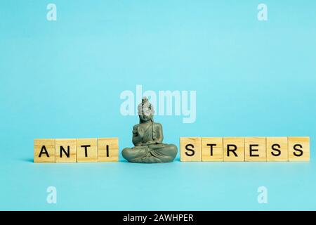 Anti-Stress-Konzept. Die Aufschrift Stressfrei auf einem reinblauen Hintergrund mit einer meditierenden Figur. Stressreduzierung und -Kontrolle. Stockfoto