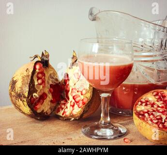 Frischer Granatapfelsaft in einer Glaskanne mit in Scheiben geschnittenen Granatäpfchen auf einem Hackbrett Stockfoto