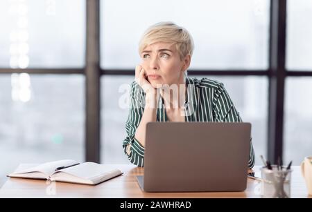 Unmotivierte Dame, Die Am Arbeitsplatz Im Modernen Büro Sitzt Stockfoto