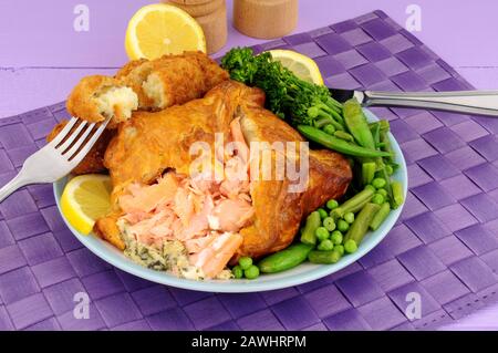 Rosafarbener Lachs, verpackt in Blätterteig mit Kartoffelkroketten und Gemüse Stockfoto
