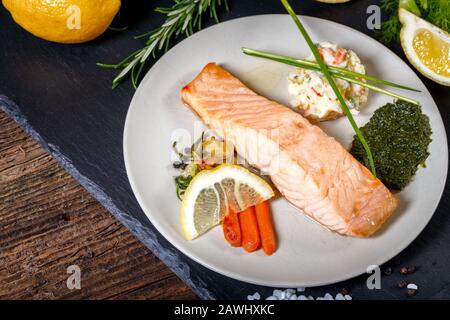 Gegrillter Lachs mit Zitrone, Kräutern und Pesto. Rote Karotten. Kartoffelsalat. Stockfoto