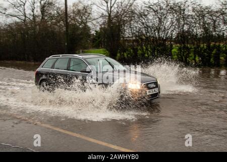 Ein Auto, das in Kirkham, Lancashire, Großbritannien, mit hoher Geschwindigkeit durch tiefes Hochwasser fährt und dabei auf einer Straße Spray aufsprüht. Februar 2020. Wetter in Großbritannien; Sturm Ciara Straßen überflutet in Kirkham. Quelle: MediaWorldImages/Alamy Live News Stockfoto