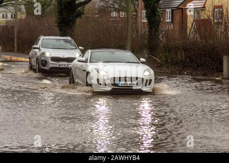 Ein Auto, das in Kirkham, Lancashire, Großbritannien, mit hoher Geschwindigkeit durch tiefes Hochwasser fährt und dabei auf einer Straße Spray aufsprüht. Februar 2020. Wetter in Großbritannien; Sturm Ciara Straßen überflutet in Kirkham. Quelle: MediaWorldImages/Alamy Live News Stockfoto