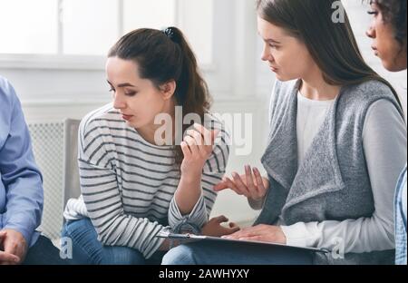 Psychotherapeut spricht mit trauriger süchtig machender Frau bei der Betreuungsgruppensitzung Stockfoto