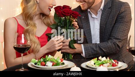 Unerkennbarer Mann, Der Roses Bouquet An Girlfriend On Date In Restaurant Gibt Stockfoto