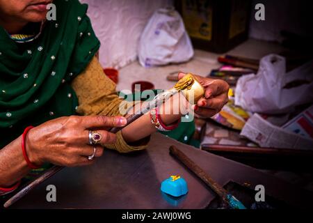 Indien, Rajasthan, Shekhawati, Nawalgarh, die traditionellen lac Bangles von Hand formt, Muster bildet, die geschmolzene Goldfarbe an der Winkelbasis anheftet Stockfoto