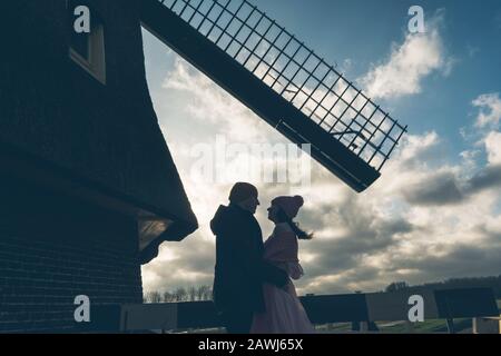 Liebevoller Mann und Frau stehen sich unter der Mühle in Holland gegenüber Stockfoto
