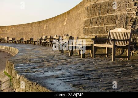 Holz-Gedenkbänke am Cobb Harbour in Lyme Regis im Februar. Dorset England GB. Stockfoto