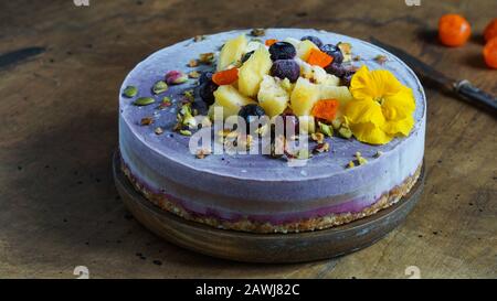 Veganer roher Käsekuchen mit Blaubeere, Kirsche, Matchtee, Orange, Cashew-Creme, Kokosbutter und Kokosmilch sowie Basis aus Mandeln, Datteln und Stockfoto