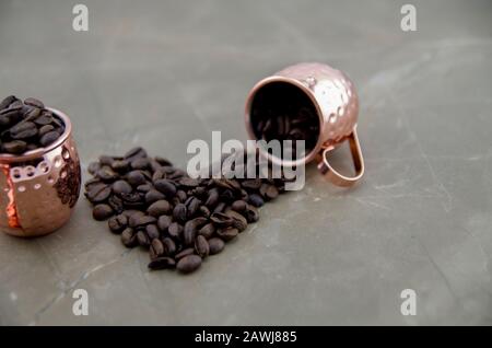 Frisch geröstete Kaffeebohnen mit Metallbecher. Zubereitung von Espresso, natürlichem Stimulans und Quelle von Antioxidantien. Ein Geschmack, der jeden Tag beginnt. Stockfoto