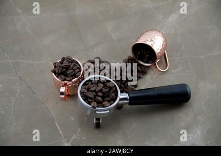 Frisch geröstete Kaffeebohnen mit Metallbecher. Zubereitung von Espresso, natürlichem Stimulans und Quelle von Antioxidantien. Ein Geschmack, der jeden Tag beginnt. Stockfoto