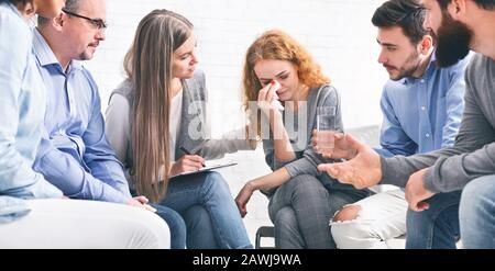 Depressive weinende Frau, die Einfühlungsvermögen von Mitgliedern der Support-Gruppe erhält Stockfoto