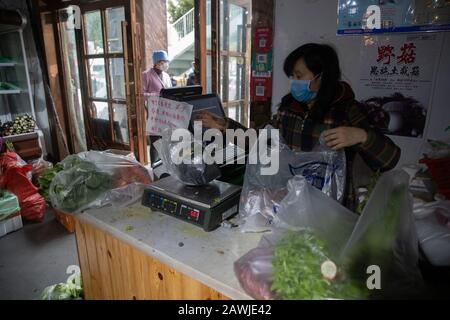 Ein chinesischer Händler, der eine Gesichtsmaske zur Vorbeugung des neuen Coronavirus und der Pneumonie trägt, verkauft Gemüse und Obst in einem Geschäft in Wuhan City, Central Stockfoto