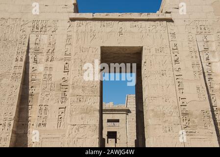 Hieroglypische Schnitzereien an der Wand am Eingang zum altägyptischen Tempel von Medinat Habu in Luxor Stockfoto