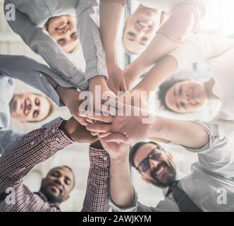 Nahaufnahme der jungen Geschäftsleute, die ihre Hände zusammenlegen. Handstapel. Einigkeit und Teamarbeit. Stockfoto