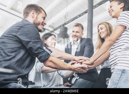 Nahaufnahme der jungen Geschäftsleute, die ihre Hände zusammenlegen. Handstapel. Einigkeit und Teamarbeit. Stockfoto